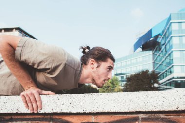 Spor yapan adam kol kaslarını çalıştırıyor. Açık havada şınav çekiyor. 