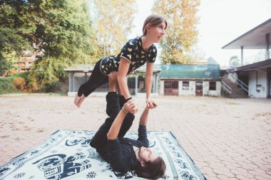 Healthy young man lying floor balancing woman doing acrobatic yoga exercise