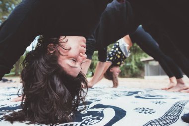 young people friends practicing stretching and yoga workout exercise together outdoors park