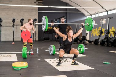 Fit young woman lifting barbells training gym cross fit concentrating on strength training, making progress towards her fitness goals