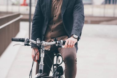 Unrecognizable contemporary stylish businessman going to work by bike commuting the carbon-free way