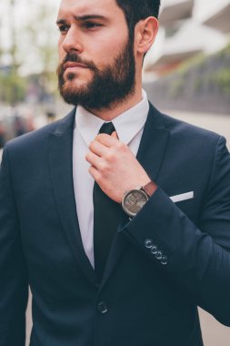 Young elegant professional executive bearded businessman posing outdoors confident and reassuring