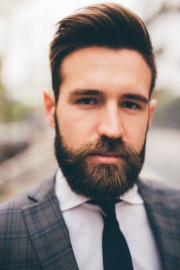 Young elegant professional executive bearded businessman posing outdoors confident and reassuring