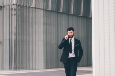 Young elegant bearded modern businessman outdoors talking smartphone having conversation