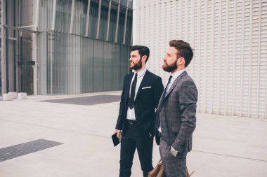 Two confident and professional elegant bearded businessmen standing outdoor posing contemplating 