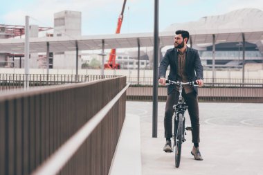 Contemporary bearded young stylish businessman going to work by bike commuting the carbon-free way