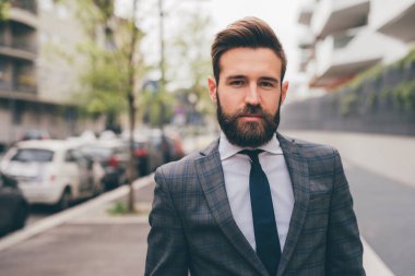 Young elegant professional executive bearded businessman posing outdoors confident and reassuring