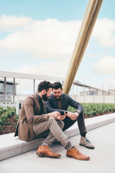Two Young Contemporary Businessman Sitting Outdoors Sharing Using Tablet Computer — Stok fotoğraf