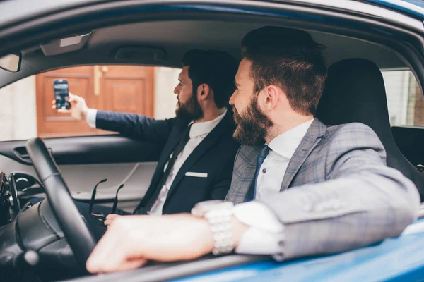 Dwóch Eleganckich Współczesnych Brodatych Biznesmenów Robiących Selfie Siedzących Samochodzie — Zdjęcie stockowe