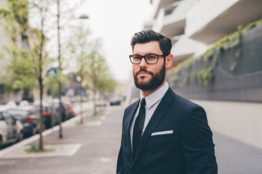 Young elegant professional executive bearded businessman posing outdoors confident and reassuring 