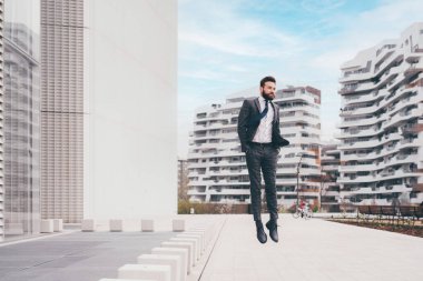 Energetic young bearded professional businessman jumping in mid-air