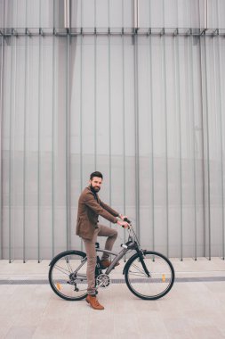 Contemporary bearded young stylish businessman going to work by bike commuting the carbon-free way