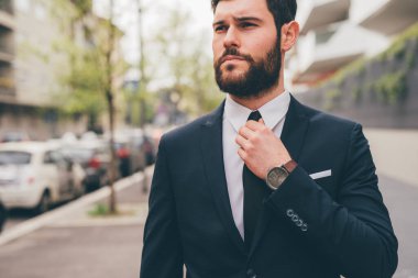 Young elegant professional executive bearded businessman posing outdoors confident and reassuring
