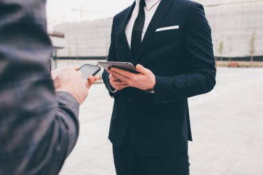 Tanımlanamayan iki zarif iş adamı tablet ve akıllı telefon kullanıyor.