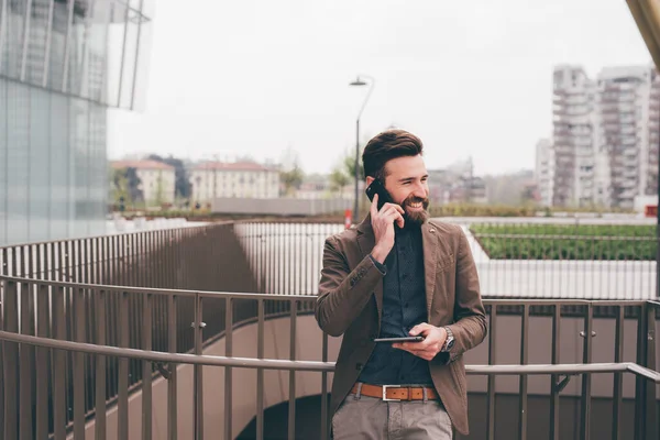 Genç Sakallı Modern Adamı Dışarıda Elinde Tabletle Akıllı Telefonlardan Konuşuyor — Stok fotoğraf
