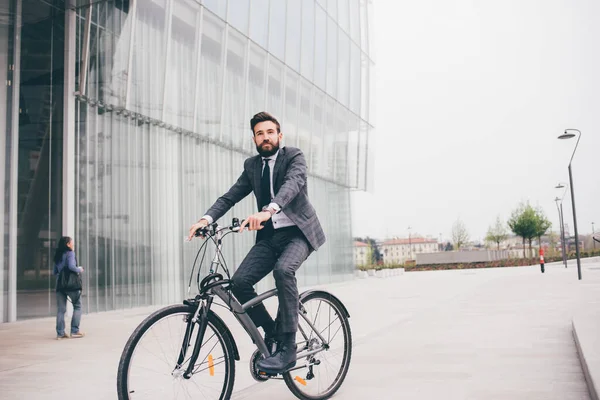 自転車で通勤する現代的なひげを生やした若いスタイリッシュなビジネスマン — ストック写真