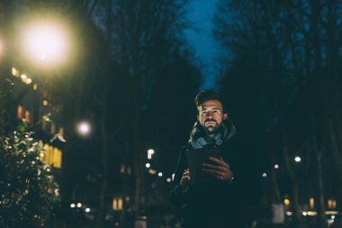 Genç işadamı gece tablet kullanıyor.