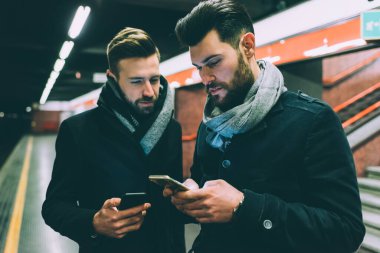 Yeraltında akıllı telefon kullanan iki genç işadamı.