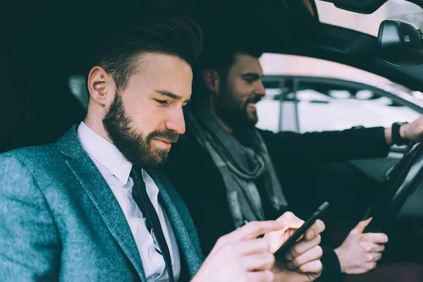 Dwóch Młodych Biznesmenów Używających Smartfona Prowadzenia Samochodu — Zdjęcie stockowe
