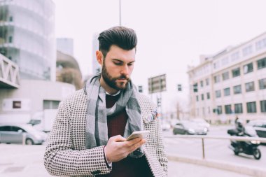 Genç sakallı iş adamı akıllı telefon kullanıyor.