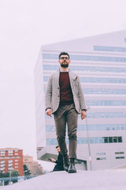 Genç iş adamı, sakallı, dışarıda yürüyor.