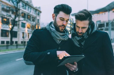 Tablet kullanan iki genç iş adamı.