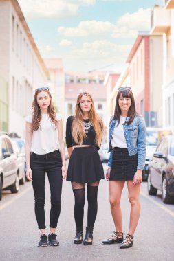 Üç genç ve mutlu bayan arkadaş dışarıda eğleniyorlar.