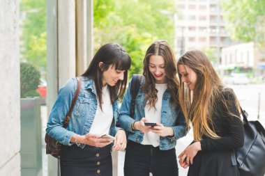 Şehirde akıllı telefon kullanan üç genç kadın milenyum kuşağı. 