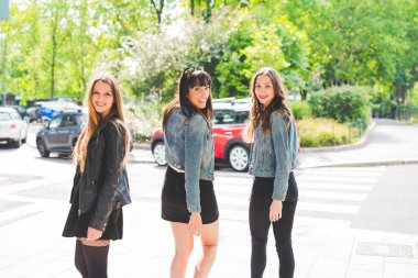 Üç genç ve mutlu bayan arkadaş dışarıda eğleniyorlar.