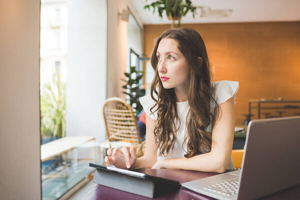 Молодая предпринимательница, работающая с компьютером и планшетом