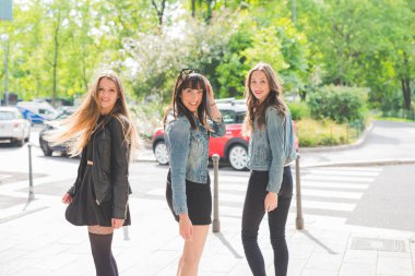 Üç genç ve mutlu bayan arkadaş dışarıda eğleniyorlar.