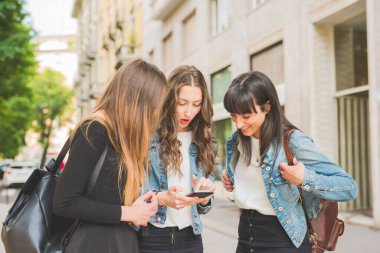 Şehirde akıllı telefon kullanan üç genç kadın milenyum kuşağı.