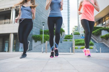 Üç genç sportif kadın açık havada antrenman yapıyor.
