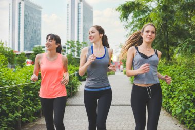 Üç genç sportif kadın açık havada antrenman yapıyor.