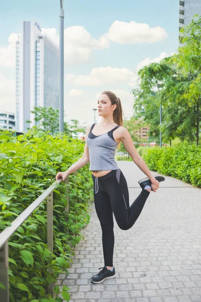 young sportive woman stretching outdoors training