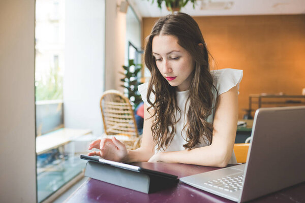 Молодая предпринимательница, работающая с компьютером и планшетом