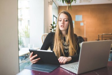 Bilgisayar ve tablet kullanan genç iş kadını.