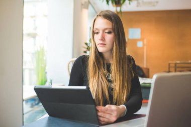 Bilgisayar ve tablet kullanan genç iş kadını.