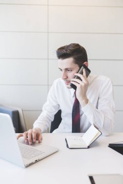 Kafkasyalı genç işadamı akıllı telefonlardan konuşuyor.