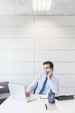 Genç Hintli işadamı akıllı telefondan konuşuyor.