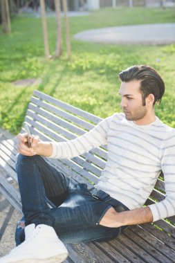 Genç adam dışarıda akıllı telefon kullanıyor.