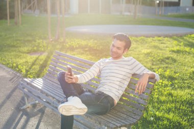 Genç adam dışarıda akıllı telefon kullanıyor.