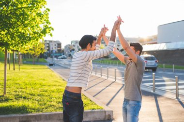Dışarıda başarıyı kutlayan iki genç çoklu etnik erkek.