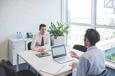 İki çok ırklı milenyum işadamı bilgisayar ofislerinde birlikte çalışıyor. 