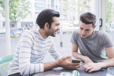 İki çok ırklı arkadaş akıllı telefon kullanarak birlikte dışarı çıktılar.