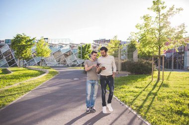 İki çok ırklı arkadaş akıllı telefon kullanarak birlikte dışarı çıktılar.