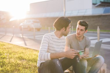 Dışarıda başarıyı kutlayan iki genç çoklu etnik erkek.