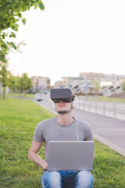Genç beyaz adam dışarıda 3 boyutlu izleme ve bilgisayar oyunu kullanıyor. 
