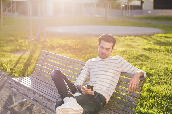 Genç Adam Dışarıda Banka Otururken Akıllı Telefon Kullanıyor — Stok fotoğraf
