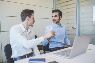 İki genç iş adamı içeride rahatça konuşuyor.